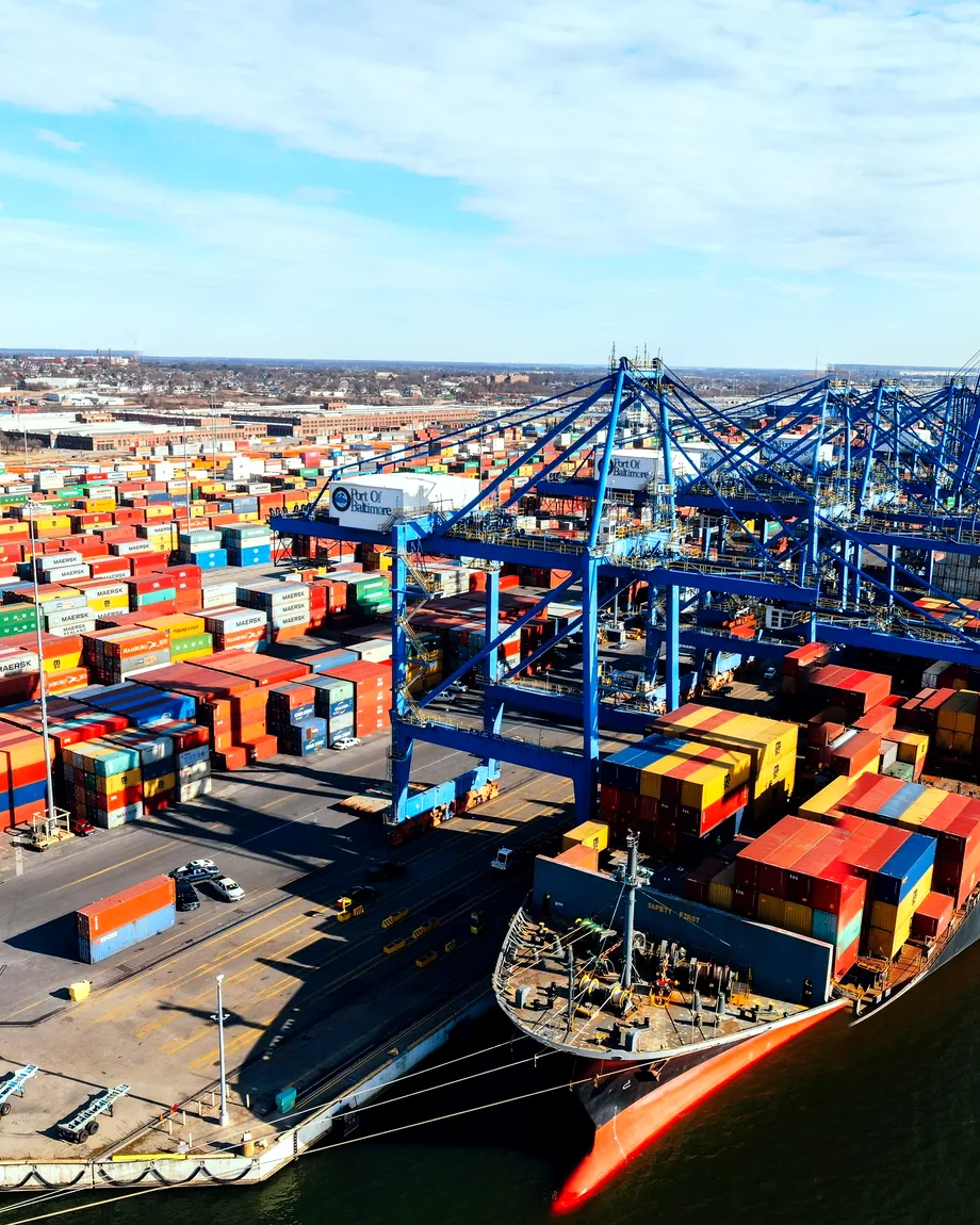 Aerial view of a busy container port with cranes and a cargo ship